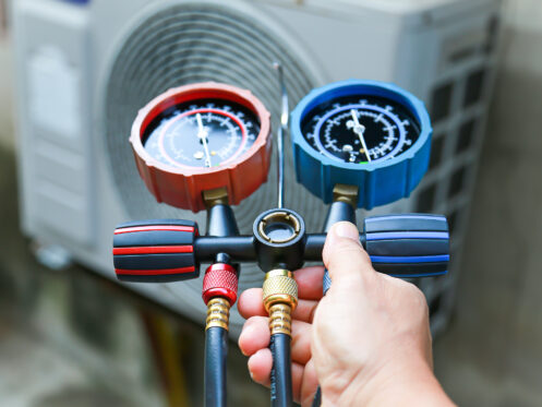 Technician checking air conditioning operation, detecting refrigerant leaks.